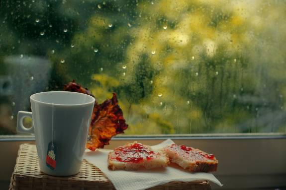 عکس کتاب و لیوان چای گرم پشت پنجره هوای بارانی 1